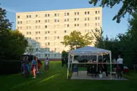Folk med forklæder snakker foran et telt med to grills og nogle arbejdsborde i boligafdelingen Axelborg i Horsens.