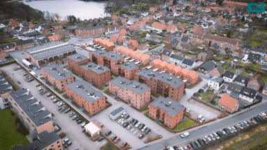 Dronefoto af sø, parkeringspladser og røde murstensbygninger i boligområdet Kongegården