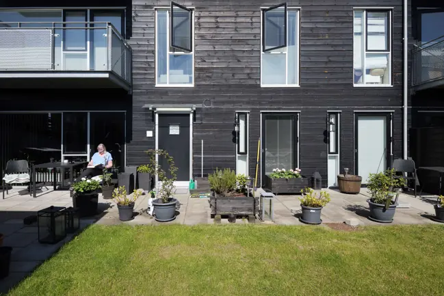 Kvinde sidder på terrasse foran sit rækkehus i boligområdet Sallingsundvej i Aalborg